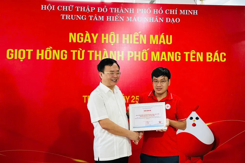 Ông Vũ Văn Hùng (bìa phải), Phó Chủ tịch Hội Chữ thập đỏ TPHCM trao thư cảm ơn cho Hiệu trưởng Trường Đại học Thủ Dầu Một z7153902520384_be4e59232864098c9baa669b5bd0f182.jpg