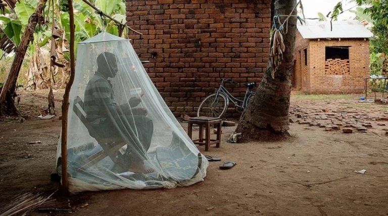 Một người dân ở Tanzania ngồi trong mùng để chống muỗi. Ảnh: Health Policy Watch