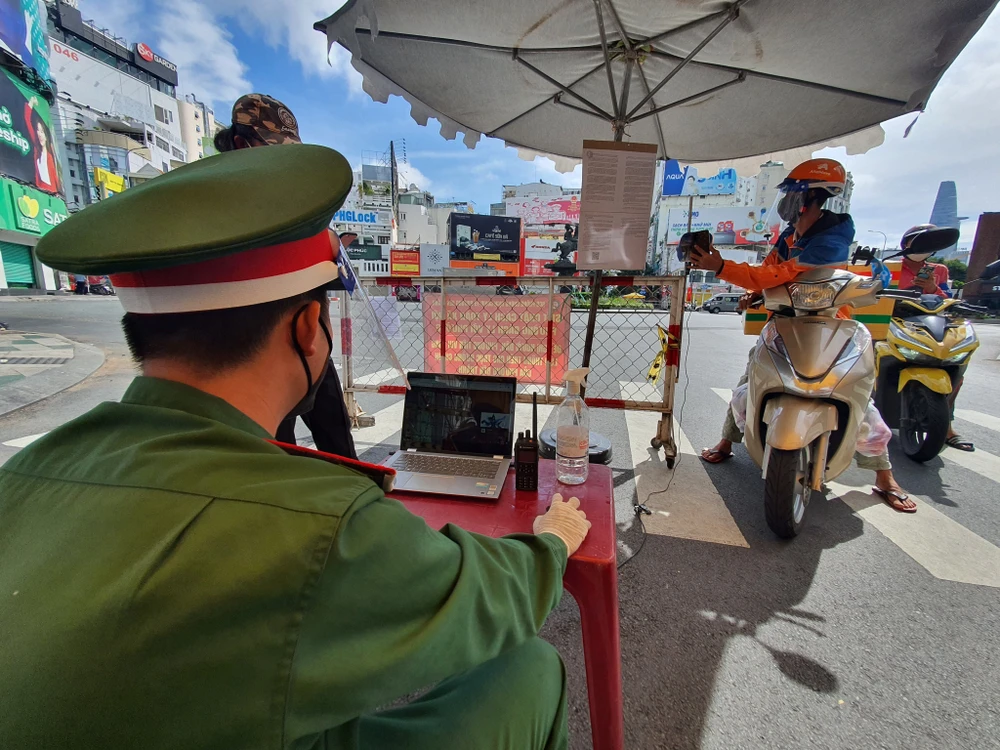 Người dân quét mã QR khai báo y tế phần mềm "di chuyển nội địa" bằng camera tự động tại chốt ngã sáu Phù Đổng, quận 1, TPHCM, sáng 3-9-2021. Ảnh: CHÍ THẠCH 