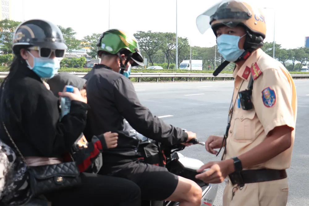 CSGT TPHCM tặng nước suối, mũ bảo hiểm tiếp sức người dân chạy xe máy về quê ăn tết. Ảnh: M.V.