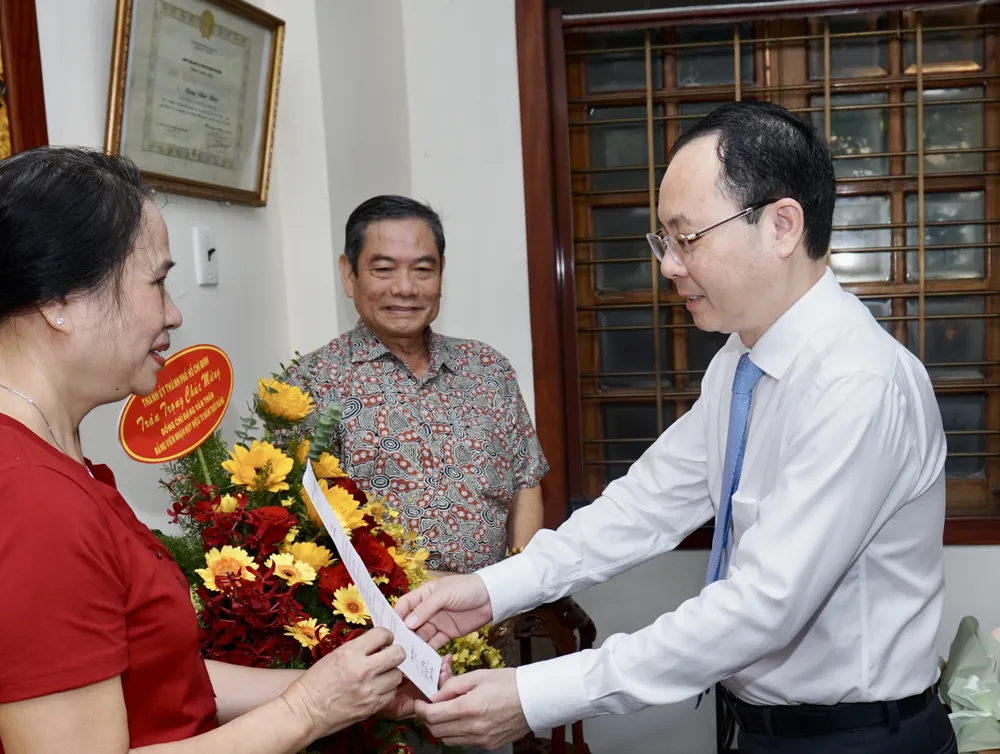 Phó Bí thư Thành ủy TPHCM Nguyễn Văn Hiếu trao quyết định tặng Huy hiệu 70 năm tuổi Đảng cho người thân của đồng chí Đặng Văn Thân. Ảnh: HOÀNG HÙNG