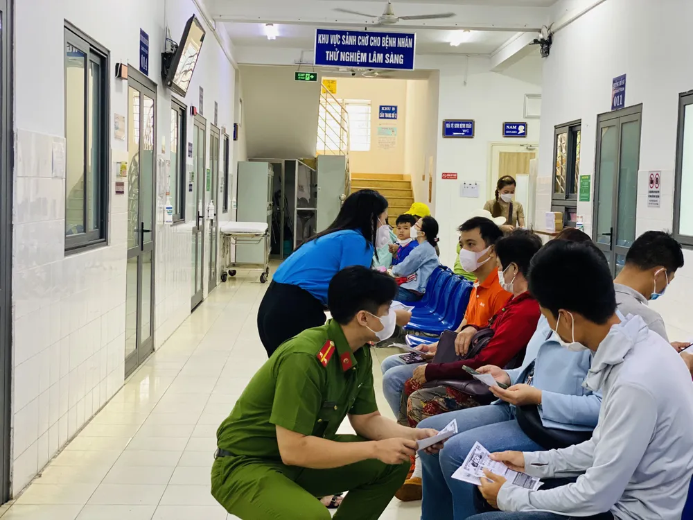 Công an phát tờ rơi tuyên truyền cho người dân ở khu khám bệnh. Ảnh: CHÍ THẠCH