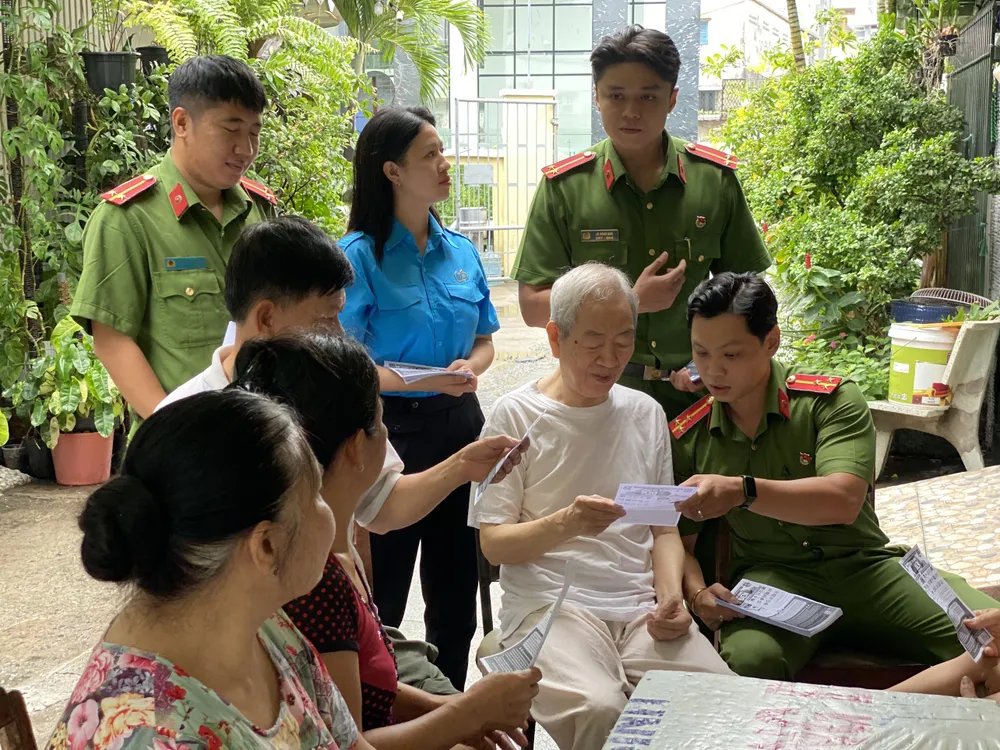 Công an, đoàn viên vào tận nhà dân để phát tờ rơi tuyên truyền. Ảnh: CHÍ THẠCH