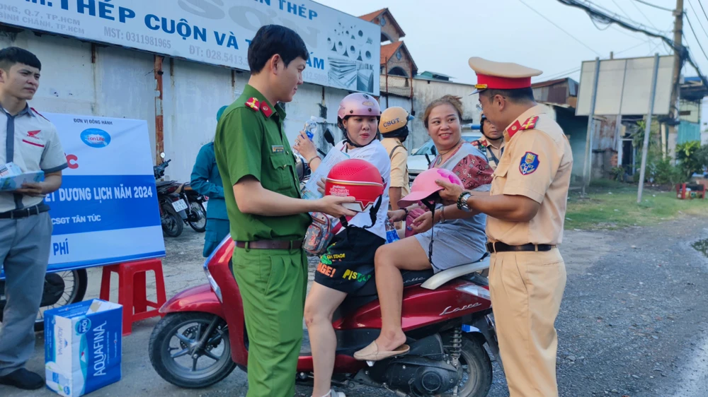 Cán bộ chiến sĩ Trạm CSGT Tân Túc phát nước, tờ rơi và nón bảo hiểm cho người dân về quê z5021880199069-9605b3d425c6cce8fcf3225664a27ee4-2713.jpg