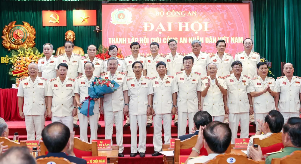 Bộ trưởng Bộ Công an Tô Lâm tặng hoa chúc mừng Ban Chấp hành Hội Cựu Công an nhân dân Việt Nam. Ảnh: VIẾT CHUNG