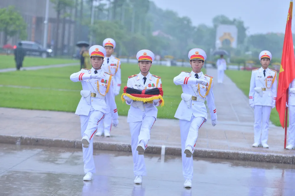 3 chiến sĩ mang khay đựng Quốc kỳ và dải băng đen bước lên bục, chuẩn bị cho lễ thượng cờ rủ z6633457985418_2190d63a9d86a74edadaa51f4fb689d1.jpg
