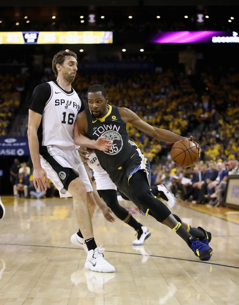 Kevin Durant (phải) đi bóng trước sự truy cản của một hậu vệ Spurs