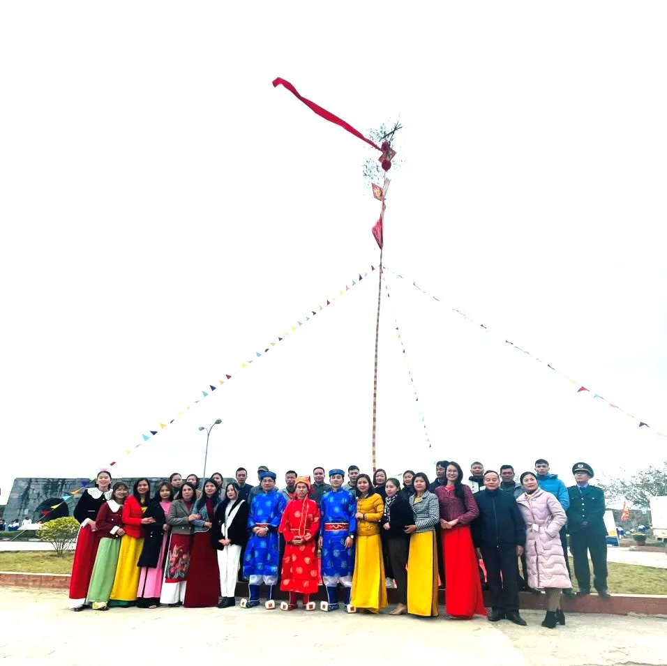 Mọi người chụp hình lưu niệm trước cây nêu