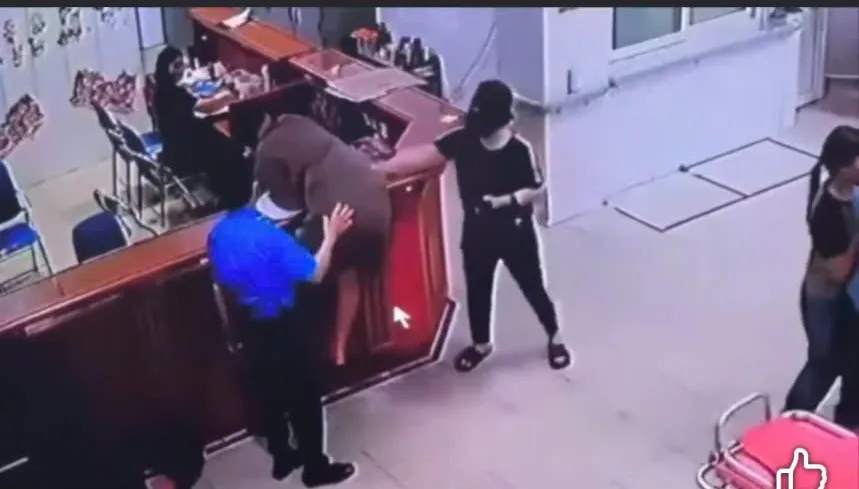 Đối tượng nhoài người vào quầy thủ tục hành hung nhân viên y tế. Ảnh cắt từ clip hành.jpg