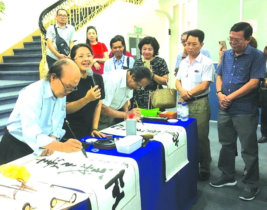 華人書畫家張路與李松年在寫書法作品。