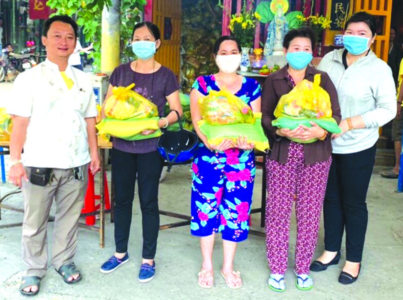 　　富山五行廟慈善組組長鄒國榮(左一)與 第十五坊祖國陣線委員會主席黃氏青美川 (右一)向貧困者派發賑濟品。