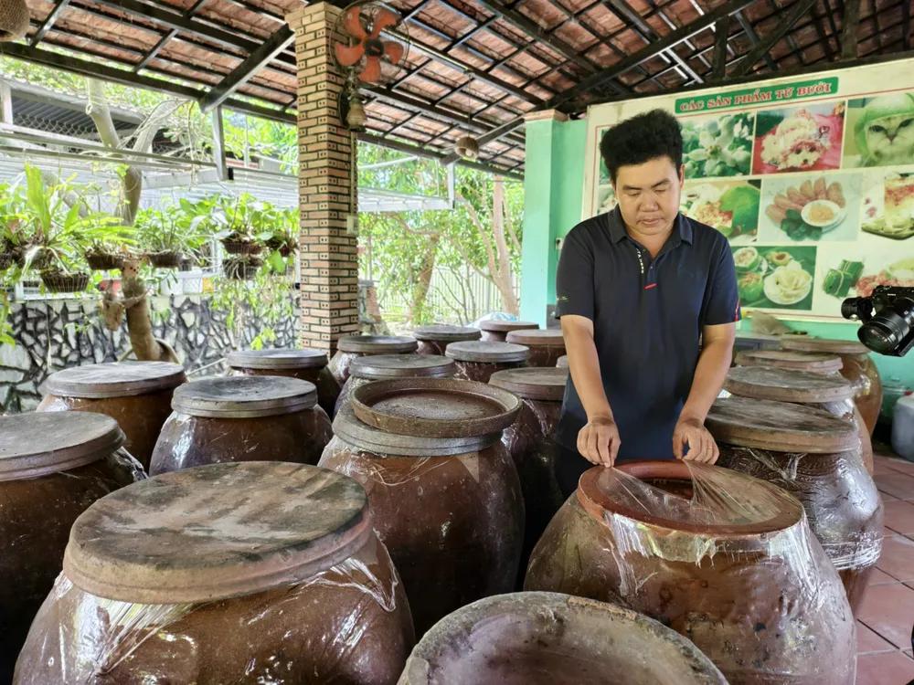 Anh Hồ Hoàng Kha bên sản phẩm nước bưởi lên men đựng trong chum sành z7178220998179_3ff4b62683b6ff08a15b8658772a3e46.jpg