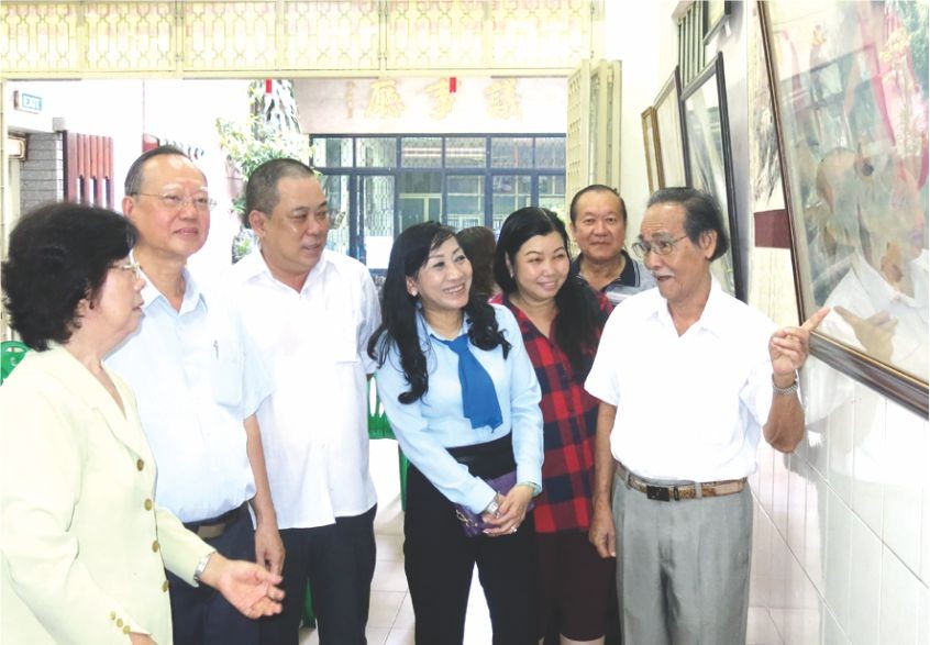 李松年書法家(右一)向參與者介紹陳列的書畫。