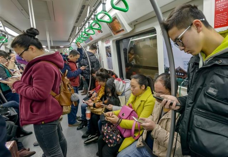 人们在乘坐地铁时低头玩手机。