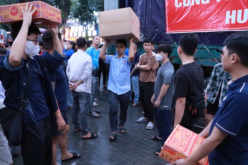 志愿者们正忙碌地将80吨物资和生活必需品装上救援车辆，送往灾区。