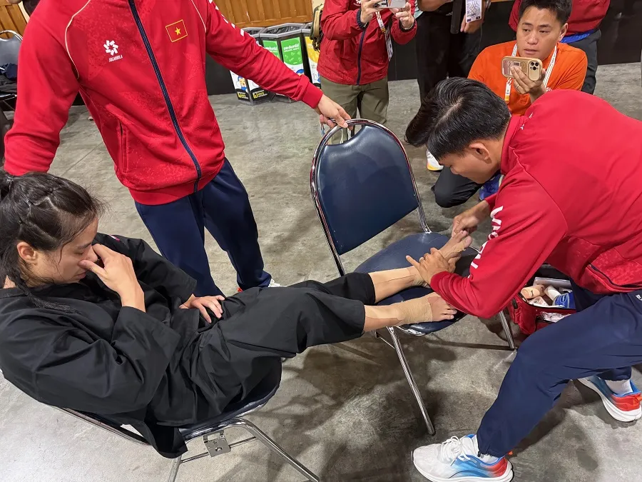 Nhân viên y tế Lê Viết Lãm giúp võ sĩ pencak silat vượt qua cơn đau sau khi vừa thi đấu trận chung kết. Ảnh: MINH CHIẾN