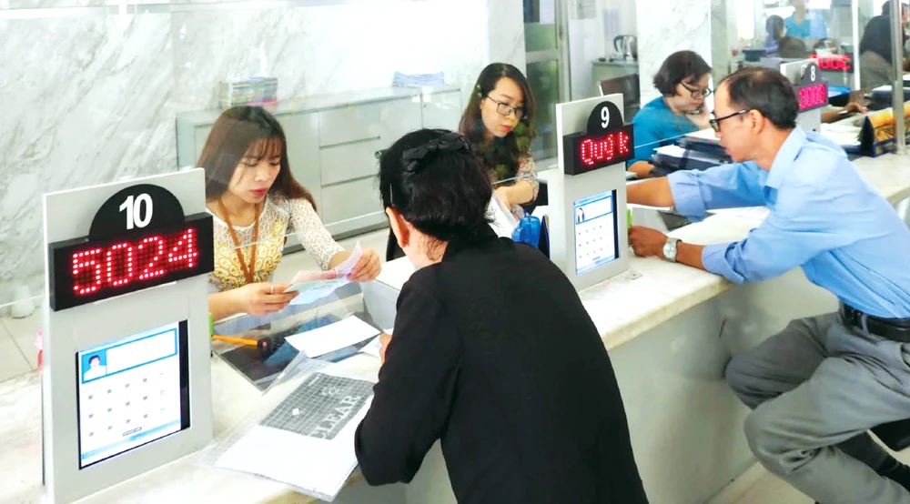 Công chức UBND quận 1, TPHCM phục vụ người dân làm thủ tục hành chính. Ảnh: HOÀNG HÙNG su menh TPHCM-7.jpg