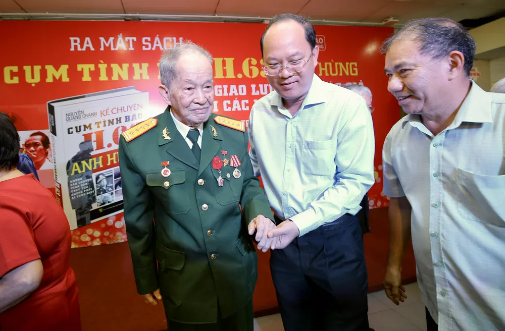 Đồng chí Nguyễn Hồ Hải ân cần đỡ Đại tá Nguyễn Văn Tàu từ sân khấu đi xuống. Ảnh: DŨNG PHƯƠNG