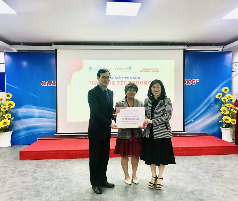 Bà Nguyễn Lệ Chi (giữa) trao tặng biểu trưng 1.000 cuốn sách cho thư viện trường ĐH Nguyễn Tất Thành