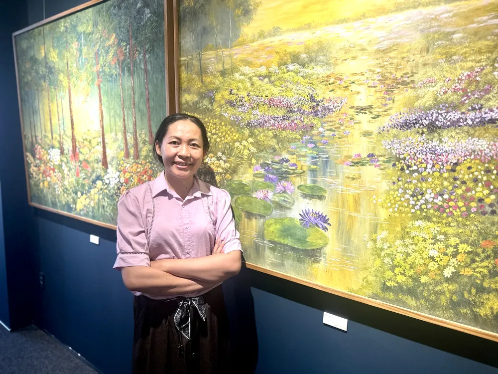 អ្នកនិពន្ធ ង្វៀន អាញ ដាវ ឈរនៅក្បែរស្នាដៃសិល្បៈរបស់គាត់នៅឯពិព័រណ៍ IMG_6744.jpg