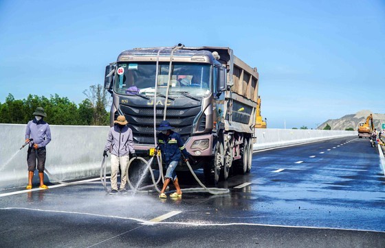 Workers spray water to wash the street.