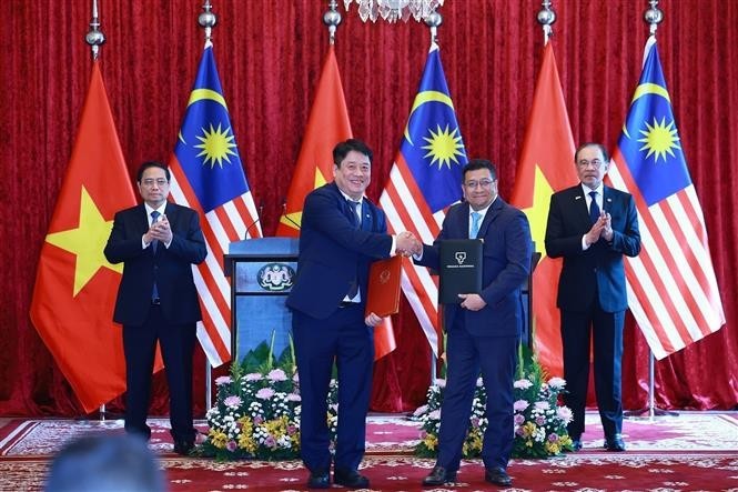 Vietnamese Prime Minister Pham Minh Chinh and his Malaysian counterpart Anwar Ibrahim on May 25 witness the signing of a memorandum of understanding on cooperation between Vietnam Electricity (EVN) and Tenaga Nasional Berhad (TNB) – Malaysia’s national power utility. (Photo: VNA) pham-minh-chin-anwar-ibrahim-cooperation-pact-vna.jpg