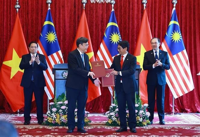 Vietnamese Prime Minister Pham Minh Chinh and his Malaysian counterpart Anwar Ibrahim witness the exchange of a letter of intent on cooperation between the Vietnam National University, HCMC and the National University of Malaysia. (Photo: VNA) vna-potal-thu-tuong-pham-minh-chinh-hoi-dam-voi-thu-tuong-malaysia-anwar-ibrahim-8053378.jpg