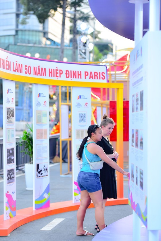 Foreign visitors are looking at pictures of the exhibition on the 50th Anniversary of the Paris Agreement on the Book Street. (Photo: SGGP)