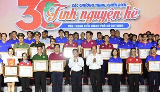 Deputy Secretary of HCMC Party’s Committee Nguyen Ho Hai and Vice Chairman of Vietnam Fatherland Front in HCMC Pham Minh Tuan are awarding certificates of merits issued by HCMC People’s Committee to groups and individuals with great contribution to summer volunteer campaigns over the past 30 years (Photo: SGGP)