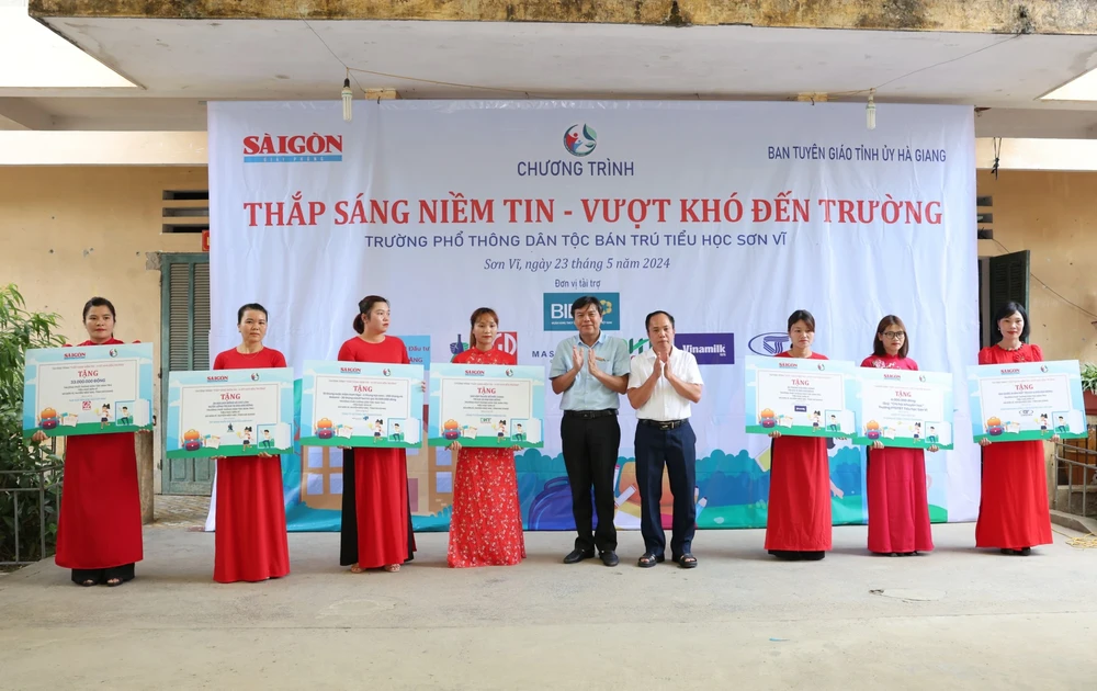 Journalist Tang Huu Phong is handing over money and items to serve the daily life of students to Principal Nguyen Hai Ha of Son Vi Ethnic Boarding Primary School (Photo: SGGP) 08.jpg