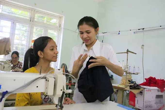 Teaching assistant Nguyen Thi Kim Ngan is using sign language to instruct her students on sewing techniques 31.jpg