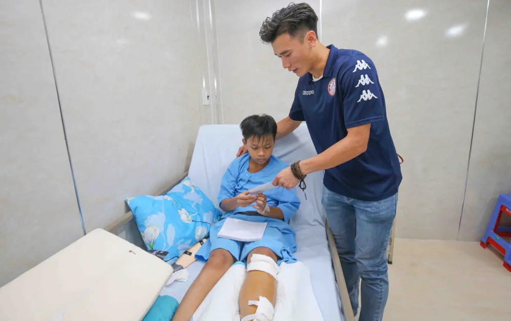 Thủ môn Bùi Tiến Dũng tặng quà cho các em học sinh trường THCS Bạch Đằng trong vụ cây phượng bật gốc. Ảnh: Dũng Phương