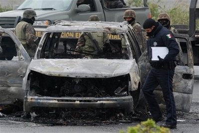Soldiers and a Police officer inspect a charred vehicle after a shootout in Juarez, Mexico, Friday, Dec. 4, 2009 Soldiers and a Police officer inspect a charred vehicle after a shootout in Juarez, Mexico, Friday, Dec. 4, 2009