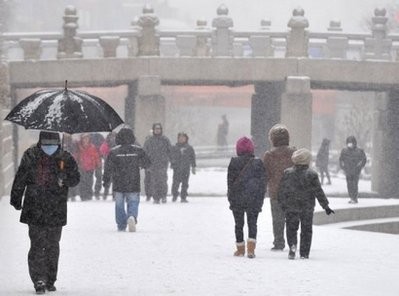 South Korean citizens walk during snow fall in central Seoul. South Korean citizens walk during snow fall in central Seoul.
