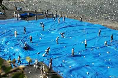HVS workers cover untreated nix grain (copper slag) with a tarp. Until a treatment plant for the toxic substance is built, local residents will be forced to live with pollution caused by the nix. ( Photo: SGGP) HVS workers cover untreated nix grain (copper slag) with a tarp. Until a treatment plant for the toxic substance is built, local residents will be forced to live with pollution caused by the nix. ( Photo: SGGP)
