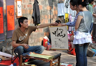 A student in jeans and T-shirt instead of a coat of old-time scholar offers words written in calligraphy style A student in jeans and T-shirt instead of a coat of old-time scholar offers words written in calligraphy style
