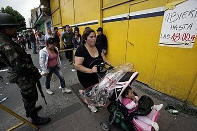 People wait in line to buy goods in a supermarket as soldiers guard the entrance, in Concepcion, Chile, on March 7. People wait in line to buy goods in a supermarket as soldiers guard the entrance, in Concepcion, Chile, on March 7.
