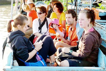 Foreign tourists enjoy going by boat on Mekong river, spending time in the heart of the Mekong Delta while learning about the southern culture. Foreign tourists enjoy going by boat on Mekong river, spending time in the heart of the Mekong Delta while learning about the southern culture.