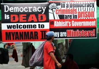 A Red-Shirt supporter walks past a placard during an anti-government protest in Bangkok on March 29, 2010. AFP photo A Red-Shirt supporter walks past a placard during an anti-government protest in Bangkok on March 29, 2010. AFP photo