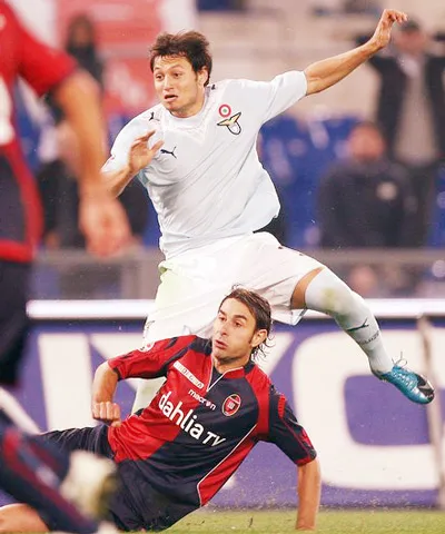 Tiền đạo Lazio Mauro Zarate (trên) trong pha tranh bóng với hậu vệ Daniele Conti (Cagliari)