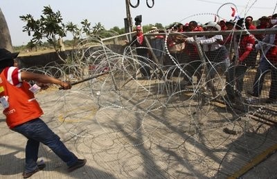 Anti-government protesters try to break a barrier to enter Thaicom compound in Pathum Thani, north of Bangkok, Thailand, Friday, April 9, 2010 Anti-government protesters try to break a barrier to enter Thaicom compound in Pathum Thani, north of Bangkok, Thailand, Friday, April 9, 2010
