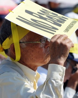 A man shields his eyes with a placard that reads No Base as he listens to an address at rally the continued presence of US airbases on Okinawa island, at Yomitan in Okinawa prefecture on April 25, 2010. A man shields his eyes with a placard that reads No Base as he listens to an address at rally the continued presence of US airbases on Okinawa island, at Yomitan in Okinawa prefecture on April 25, 2010.