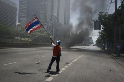 A 'Red Shirt anti-governement protester waves a national flag during clashes with Thai soldiers (not seen) in Bangkok. A 'Red Shirt anti-governement protester waves a national flag during clashes with Thai soldiers (not seen) in Bangkok.