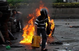 A Thai red-shirt anti-government protestor runs with a jerry-can after setting tyres on fire on Rama IV road in Bangkok on May 18, 2010. AFP photo A Thai red-shirt anti-government protestor runs with a jerry-can after setting tyres on fire on Rama IV road in Bangkok on May 18, 2010. AFP photo
