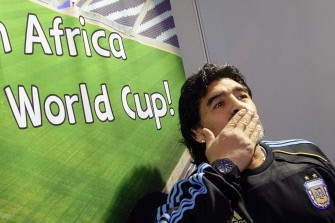 Argentina coach Diego Maradona gestures close to a poster upon his arrival with his squad at the O. R. Tambo international airport on May 29, 2010. AFP photo Argentina coach Diego Maradona gestures close to a poster upon his arrival with his squad at the O. R. Tambo international airport on May 29, 2010. AFP photo