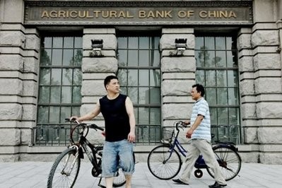 Two men push their bicycles past a Shanghai branch of the Agricultural Bank of China on June 30, 2010. Two men push their bicycles past a Shanghai branch of the Agricultural Bank of China on June 30, 2010.