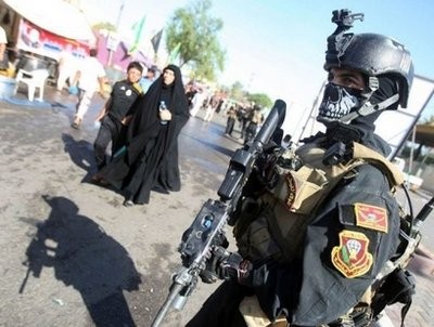 A member of the Iraqi anti-terrorism forces stands guard as Shiite Muslim pilgrims walk to Kadhimiyah A member of the Iraqi anti-terrorism forces stands guard as Shiite Muslim pilgrims walk to Kadhimiyah