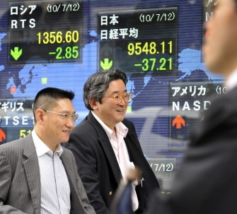 Businessmen walk past a share price board in Tokyo on July 12, 2010. AFP Businessmen walk past a share price board in Tokyo on July 12, 2010. AFP