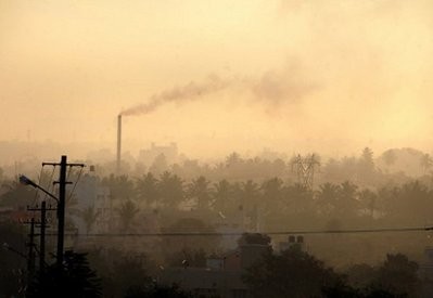 A factory chimney in a residential area emits smoke as haze casts a blanket over Bangalore, India. A factory chimney in a residential area emits smoke as haze casts a blanket over Bangalore, India.