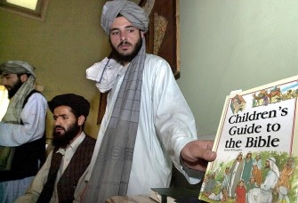 (AFP FILES) This file photo taken on September 6, 2001 shows an unidentified Taliban foreign ministry official displaying a book allegedly siezed from the offices of the non-governmental organisation group International Assistance Mission to journalists in Kabul after the Taliban militia expelled the staff of two Christian aid agencies, including the IAM, the previous week. (AFP FILES) This file photo taken on September 6, 2001 shows an unidentified Taliban foreign ministry official displaying a book allegedly siezed from the offices of the non-governmental organisation group International Assistance Mission to journalists in Kabul after the Taliban militia expelled the staff of two Christian aid agencies, including the IAM, the previous week.